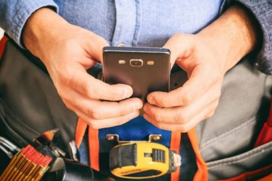 Técnico fazendo o relatório de visita técnica no celular